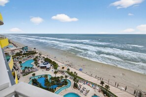 A beach resort with a pool area, beach chairs, and a view of the ocean. - Vista Bleu - Ocean Walk (Daytona Beach)
