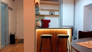 Cocina compacta con mostrador, dos taburetes y una mesa de comedor.