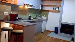 Una cocina moderna con una isla central, taburetes de bar, microondas y horno integrado.