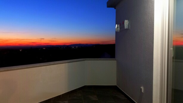 Un balcón con vista a la puesta de sol sobre el horizonte urbano.