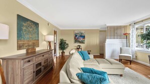 Un salon avec un canapé beige, un meuble en bois et deux tableaux accrochés au mur.