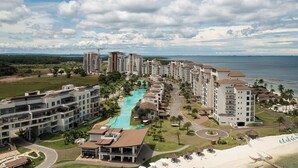 A coastal hotel with multiple high-rise buildings, a central swimming pool, and a beach area.
