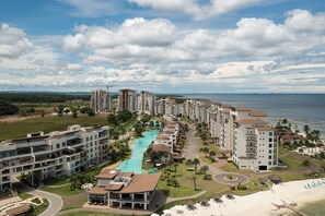 A coastal hotel with multiple high-rise buildings, a central swimming pool, and a beach area.