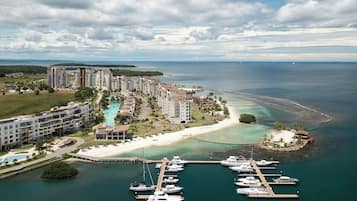 Un complejo turístico costero con varios edificios de gran altura, un puerto deportivo con yates y una zona de playa.