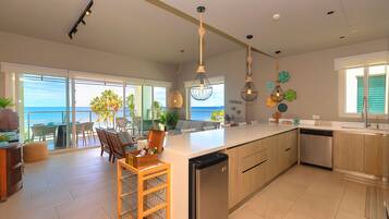 Una cocina amplia con una isla grande, luces colgantes modernas y vistas al océano.