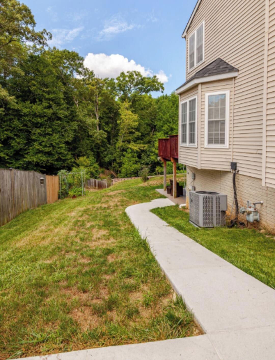 A residential backyard with a lawn, a wooden fence, and a house.