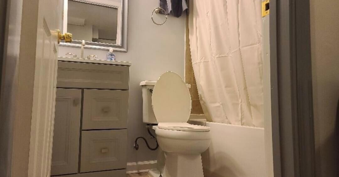 Un baño con inodoro, lavabo, espejo y cortina de ducha.