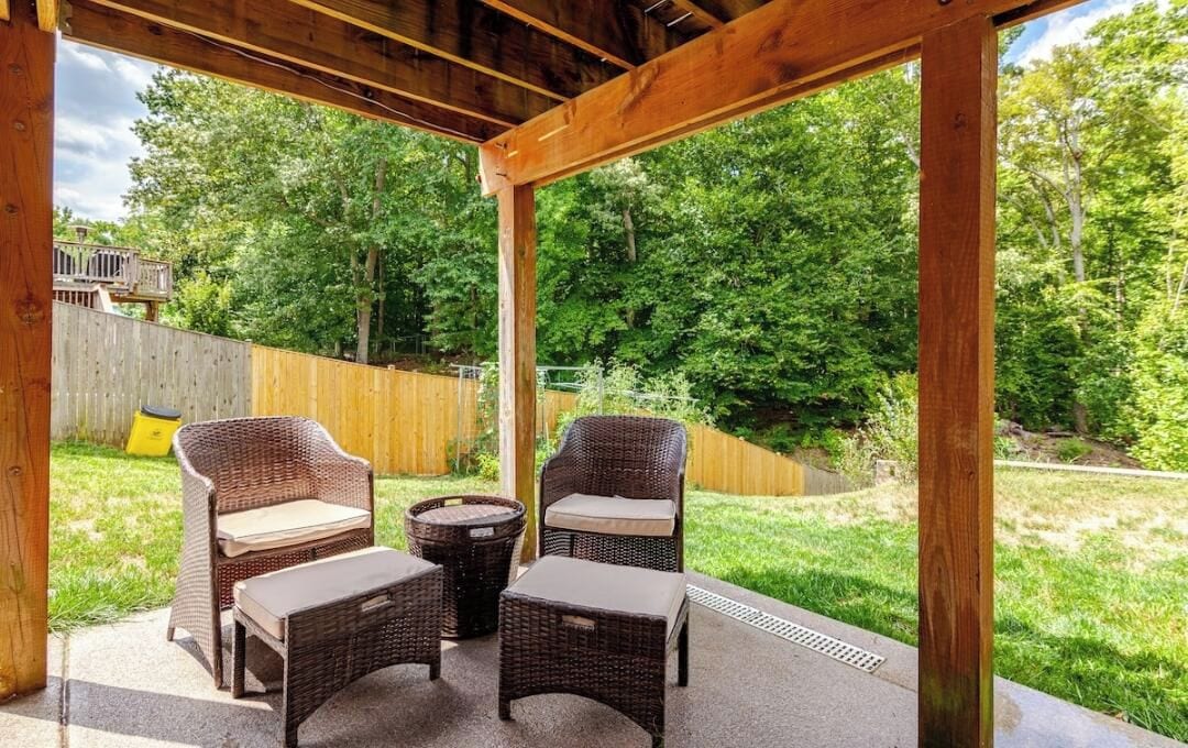 An outdoor patio with wicker furniture and a wooden pergola structure.