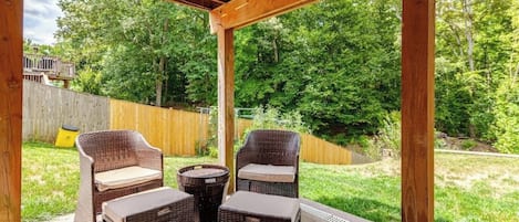 An outdoor patio with wicker furniture and a wooden pergola structure.