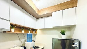 A kitchen with white cabinets, a water dispenser, a stainless steel refrigerator, and potted plants on shelves. - Cozy 2BR Condo at Seawind Davao • Smart Lock • Netflix 4K & YouTube Premium (Davao City)
