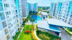 A high-rise residential building with multiple balconies, a swimming pool, and a well-maintained garden area. - Cozy 2BR Condo at Seawind Davao • Smart Lock • Netflix 4K & YouTube Premium (Davao City)