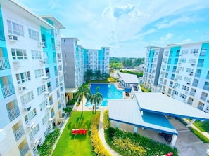 A high-rise residential building with multiple balconies, a swimming pool, and a well-maintained garden area. - Cozy 2BR Condo at Seawind Davao • Smart Lock • Netflix 4K & YouTube Premium (Davao City)