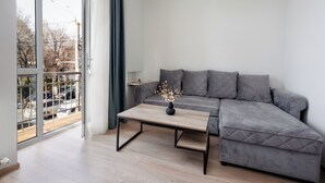 Una sala moderna con un sofá seccional gris, una mesa de centro de madera y vistas a través de un amplio ventanal corredero.