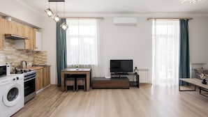 Un apartamento moderno con cocina, comedor y sala de estar. Cuenta con lavadora, estufa y televisor de pantalla plana.