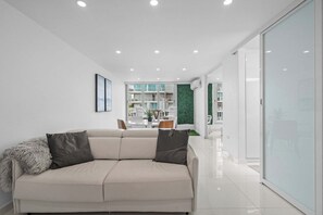 Un salon moderne avec un canapé beige, un plaid moelleux et un coussin foncé.