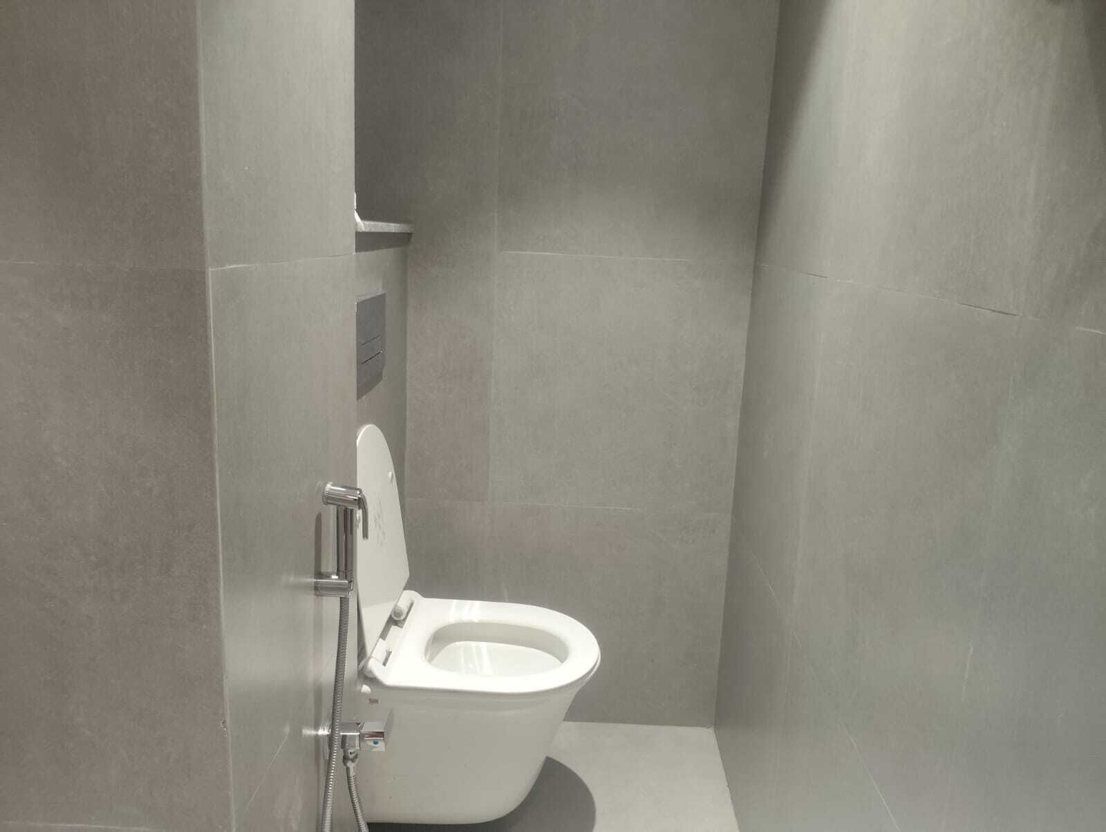 A modern bathroom with a toilet, a shower, and a wall-mounted control panel.