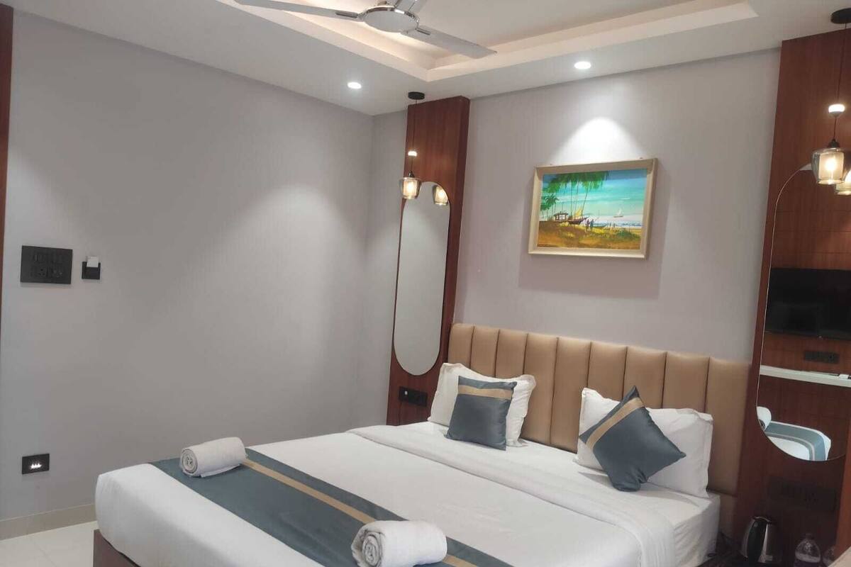 A hotel room with a large bed, a ceiling fan, a painting on the wall, and a TV on the right side.