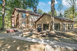 A two-story wooden cabin with a hot tub, outdoor seating, and a grill area. - Deer Run Lodge/Indoor Pool/Basketball/Hot Tub (Terre Haute)