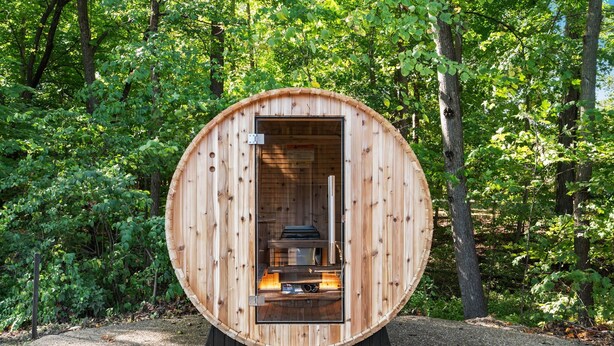 A wooden sauna structure with a bench inside, surrounded by a forest. - Deer Run Lodge/Indoor Pool/Basketball/Hot Tub (Terre Haute)