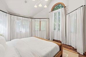 A bedroom with a large bed, white curtains, a wooden headboard, and a view of greenery outside. - Deer Run Lodge/Indoor Pool/Basketball/Hot Tub (Terre Haute)