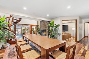 Un vaste espace de vie comprenant une table à manger en bois, des chaises, un escalier en colimaçon et une cheminée.
