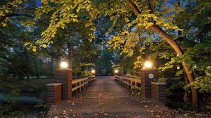 A wooden bridge with brick pillars and lights, surrounded by trees and fallen leaves. - Deer Run Lodge/Indoor Pool/Basketball/Hot Tub (Terre Haute)