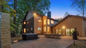 A modern two-story house with a patio area featuring a hot tub, outdoor seating, and a barbecue grill. - Deer Run Lodge/Indoor Pool/Basketball/Hot Tub (Terre Haute)