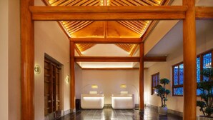 A spacious lobby with a high ceiling and wooden beams, two reception desks, and potted plants. - Lan Feng Hotel (Xi'an)