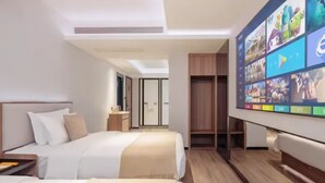 Une chambre d’hôtel moderne, dotée d’un grand lit, d’un bureau et d’un téléviseur fixé au mur, qui diffuse différentes chaînes.