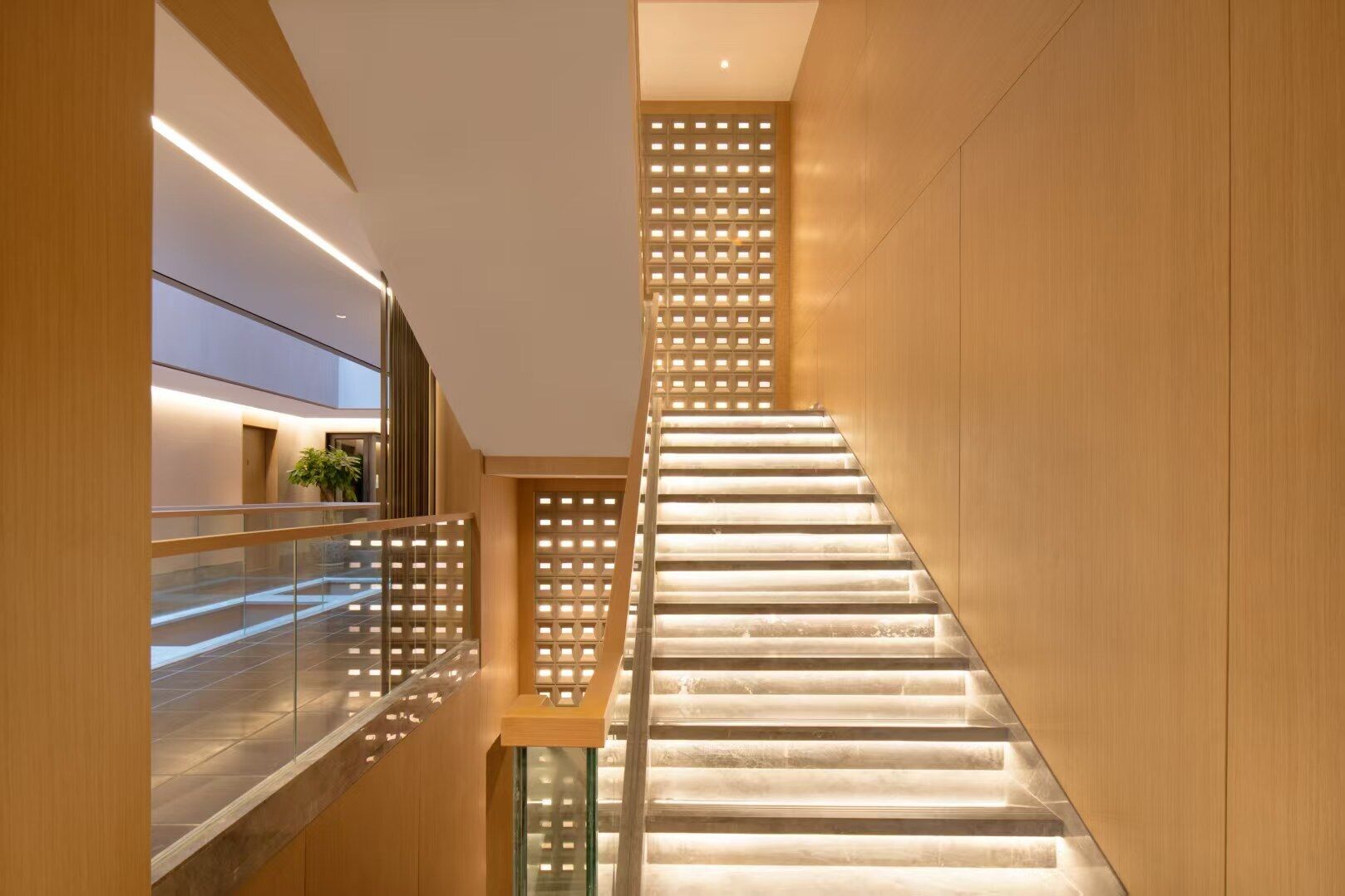 A modern interior with a staircase, wooden walls, and a glass railing.