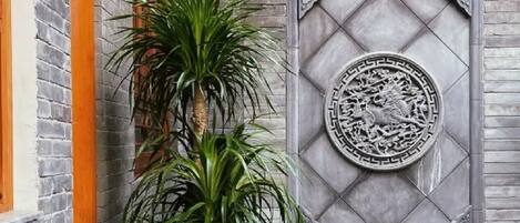 A traditional courtyard with a stone wall, a decorative circular emblem, and a water feature with aquatic plants.