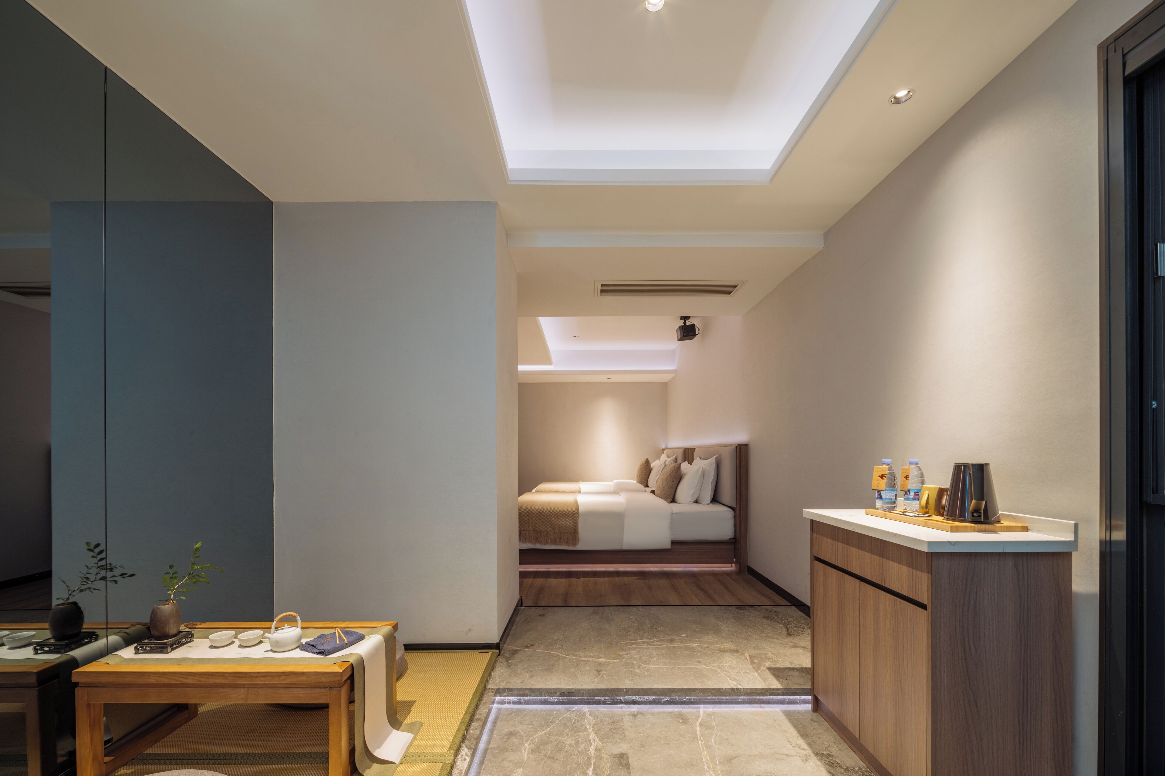 A modern hotel room with a skylight, a small dining area, and a bed with a nightstand.