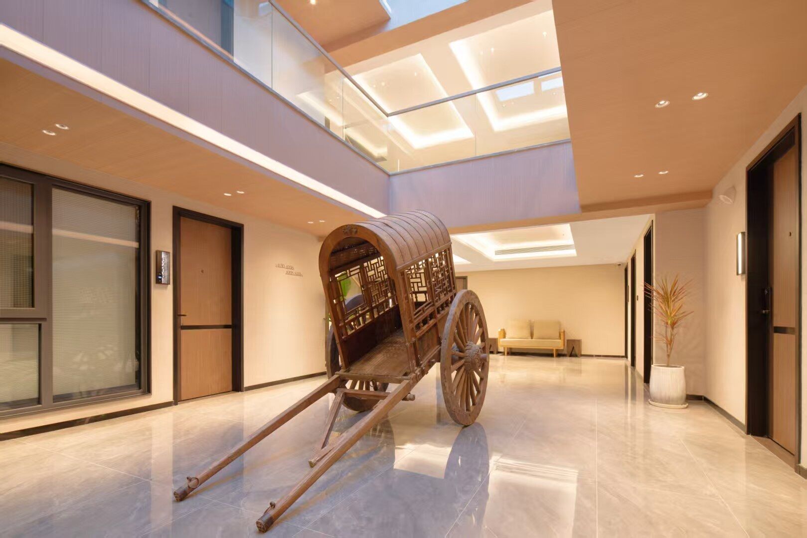 Un moderno vestíbulo de hotel con un carruaje de madera en el centro, un sofá y una planta en maceta.