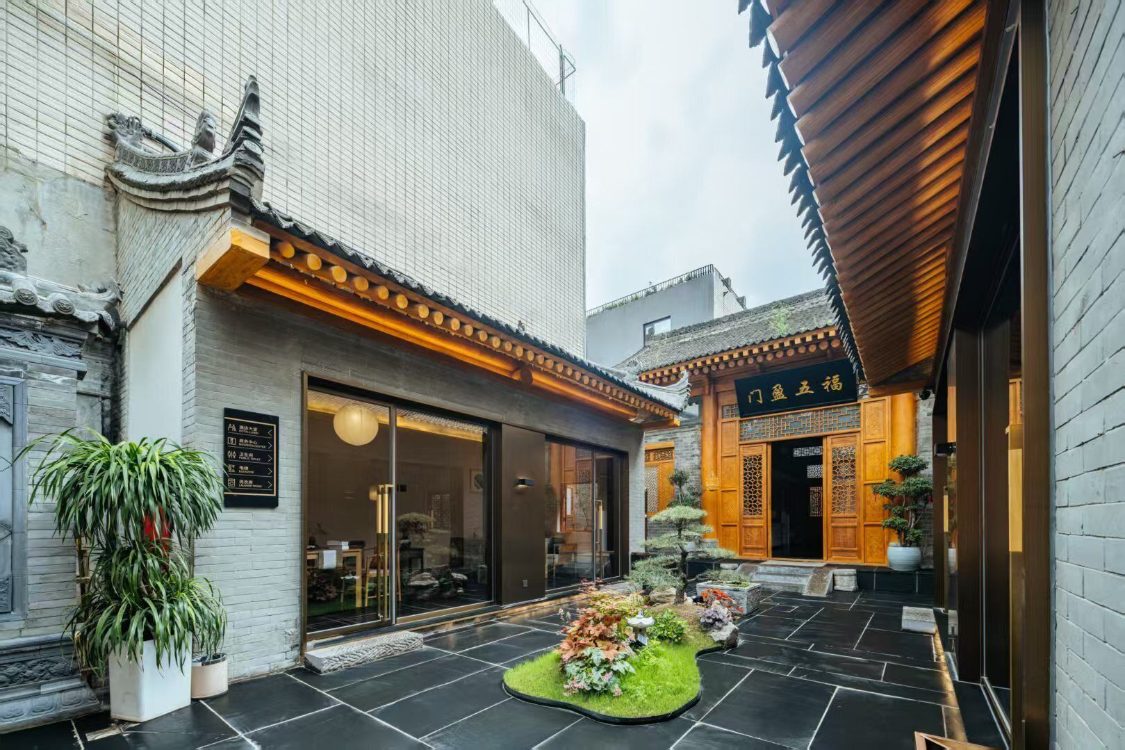 A traditional courtyard with a restaurant, potted plants, and a small garden.