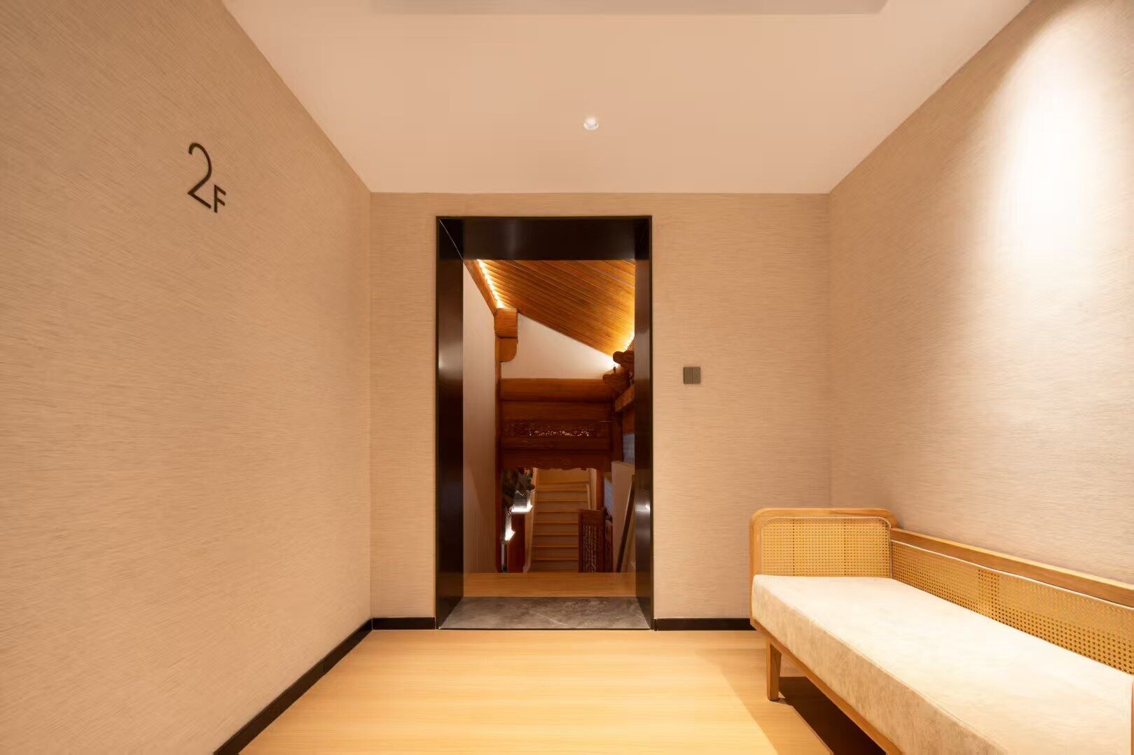 A hallway with a wooden bench, a door labeled "2F", and a staircase leading to another room.