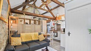 A cozy living room with a sofa, a coffee table, and a kitchen area with a stove and cabinets.