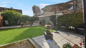 A backyard with a patio area, a fire pit, outdoor furniture, and a large umbrella.
