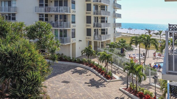 A multi-story hotel with balconies overlooking a beach.