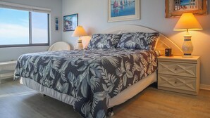 A bedroom with a bed, two bedside tables, a window, and wall art. - Riviera Beach Club 1102 - 2B/2B Dream Vacation Condo Amazing Gulf Views! (Fort Myers Beach)