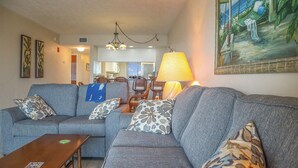A living room with a sofa set, a wooden coffee table, and a lamp. - Riviera Beach Club 1102 - 2B/2B Dream Vacation Condo Amazing Gulf Views! (Fort Myers Beach)