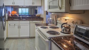 A compact kitchen with white cabinets, a stove, microwave, and a toaster. - Riviera Beach Club 1102 - 2B/2B Dream Vacation Condo Amazing Gulf Views! (Fort Myers Beach)
