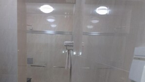Um banheiro moderno com box de vidro, vaso sanitário e porta-toalhas.