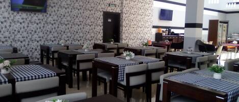 Um restaurante com várias mesas, cada uma com toalha xadrez e arranjos florais.