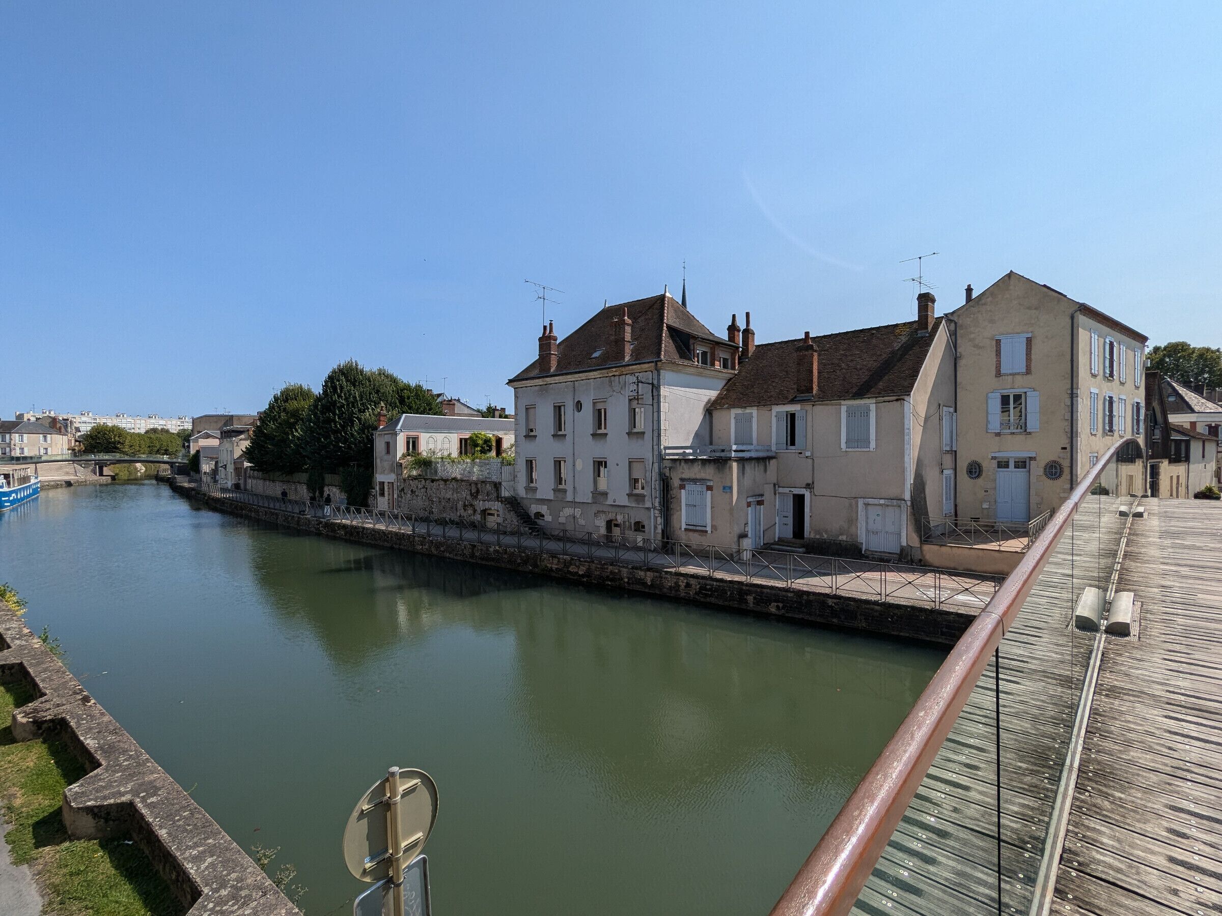A riverside building with a stone wall and a wooden walkway.