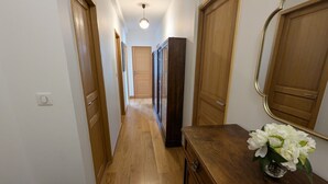 A hallway with wooden doors, a bench, and a vase with flowers.