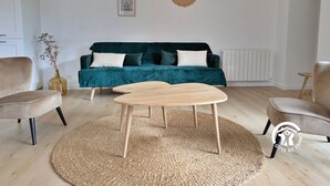 Un salon moderne avec un canapé de couleur turquoise, deux tables basses en bois et un tapis tissé.