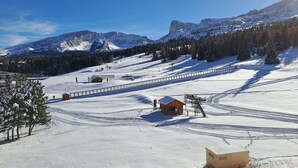 Un paysage de montagne enneigé avec des pistes de ski, un petit chalet en bois et un télésiège.