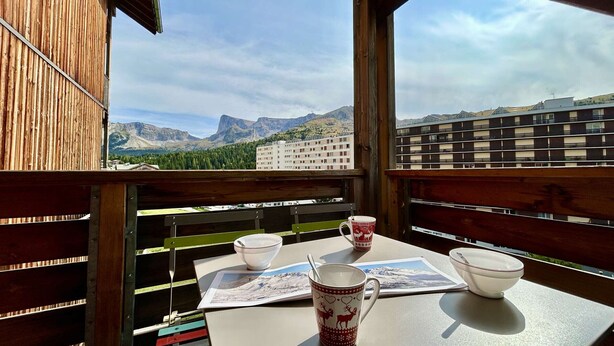 A balcony with a table, chairs, and a scenic mountain view.