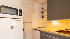 A compact kitchen with a microwave, stove, and sink.