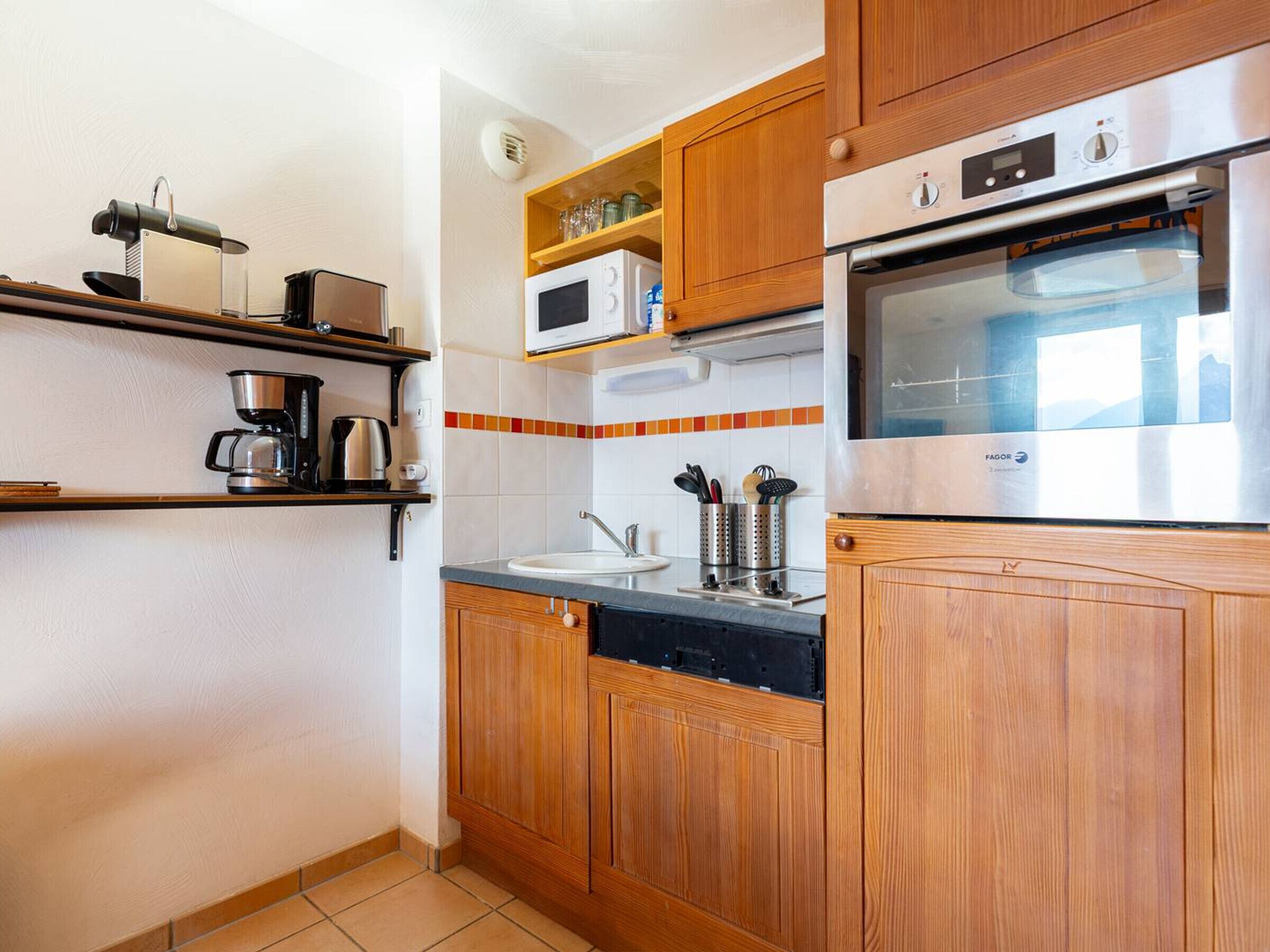 A kitchen with wooden cabinets, a microwave, an oven, a coffee maker, and a sink.